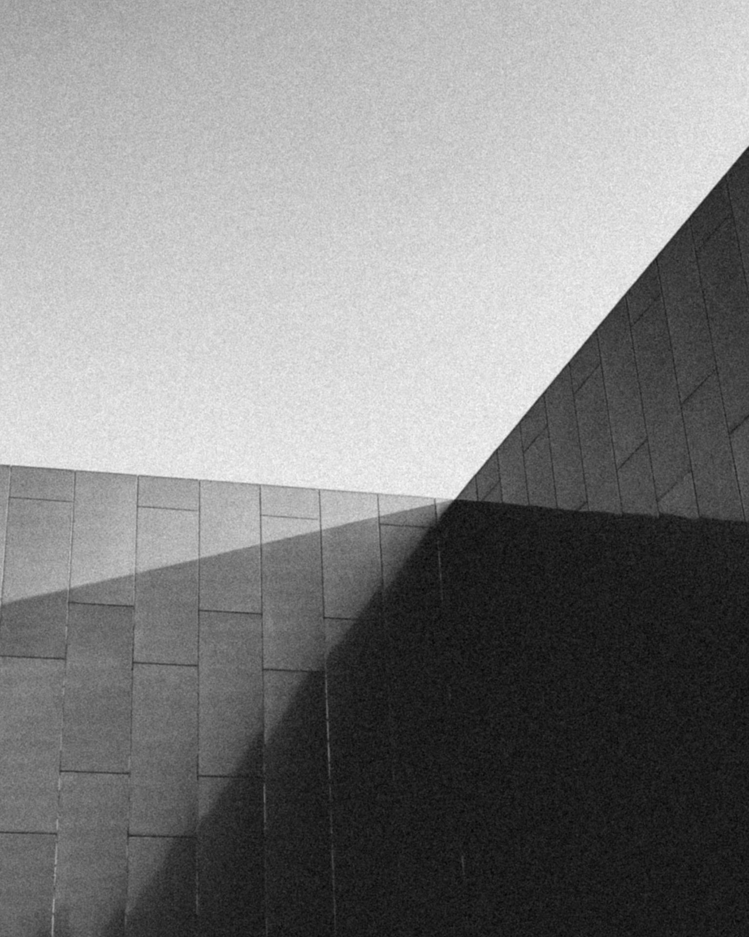 Parede de pedra escura com sombra diagonal, em plano fechado
